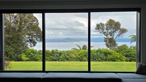 Una habitación con un ventanal grande que ofrece vistas a un área verde y un cuerpo de agua.