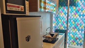 Eine Küche mit Kühlschrank, Mikrowelle und einem Fenster mit farbigem Buntglas.