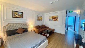 A hotel room with a large bed, a sofa, a small table with a vase, and artwork on the walls. - Bay Luxury Villa OCP2 - Self Checkin (Nghia Tru)