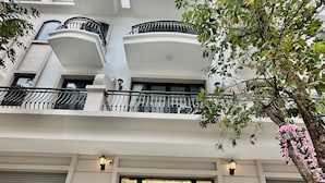 A multi-story hotel with a modern facade, a glass entrance, and a staircase leading to the interior. - Bay Luxury Villa OCP2 - Self Checkin (Nghia Tru)