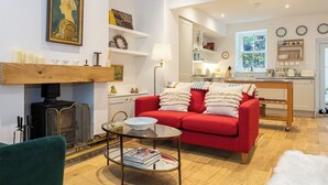 A living room with a red sofa, a glass coffee table, a fireplace, and a kitchen in the background.
