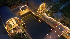 A water feature with a heart-shaped light outline, surrounded by potted plants and a wooden deck. - TamCoc Moon An Bungalow & Cafe (Nam Hoa Lu)