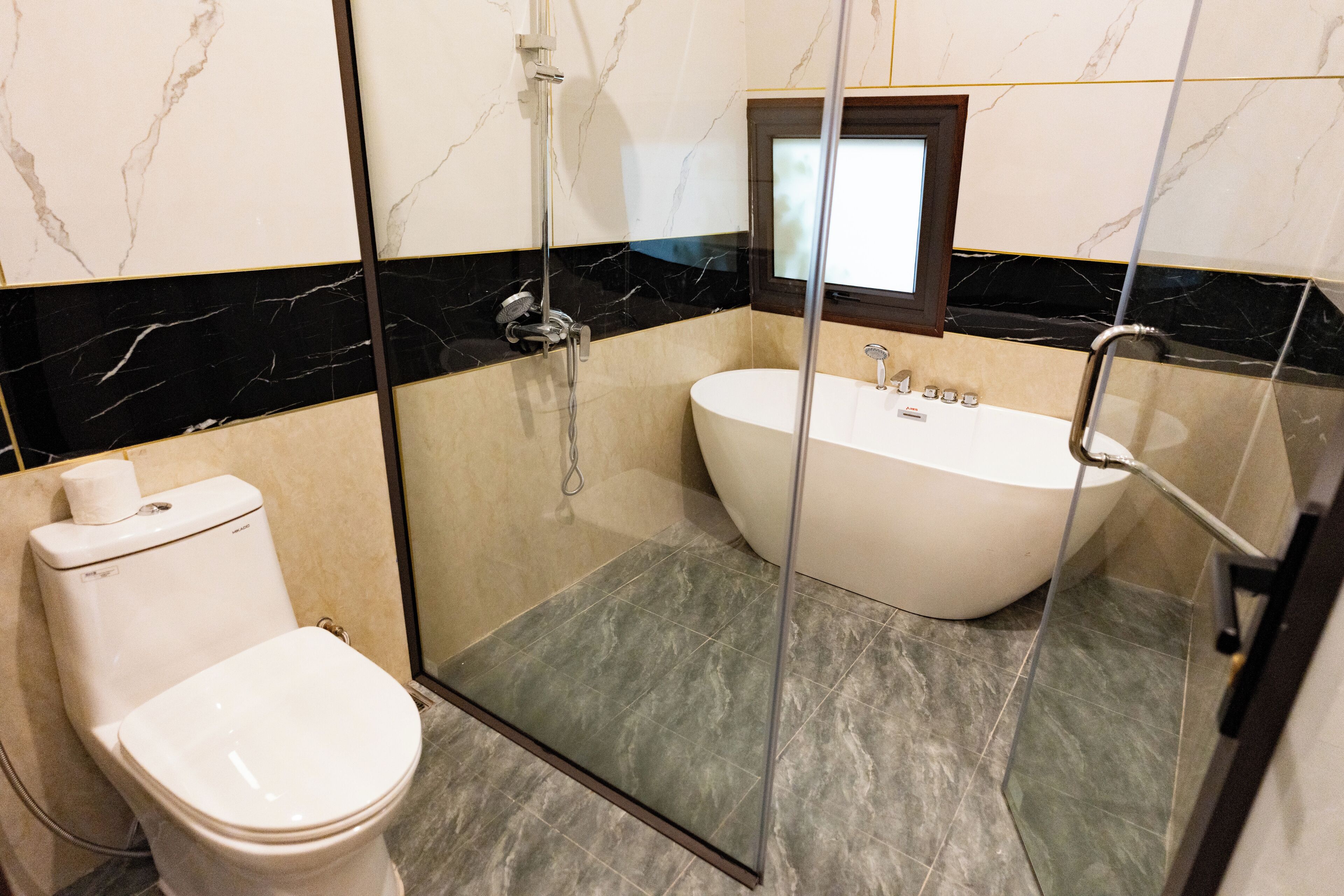Une salle de bain moderne avec une douche à parois de verre, des toilettes blanches et une baignoire sur pieds.