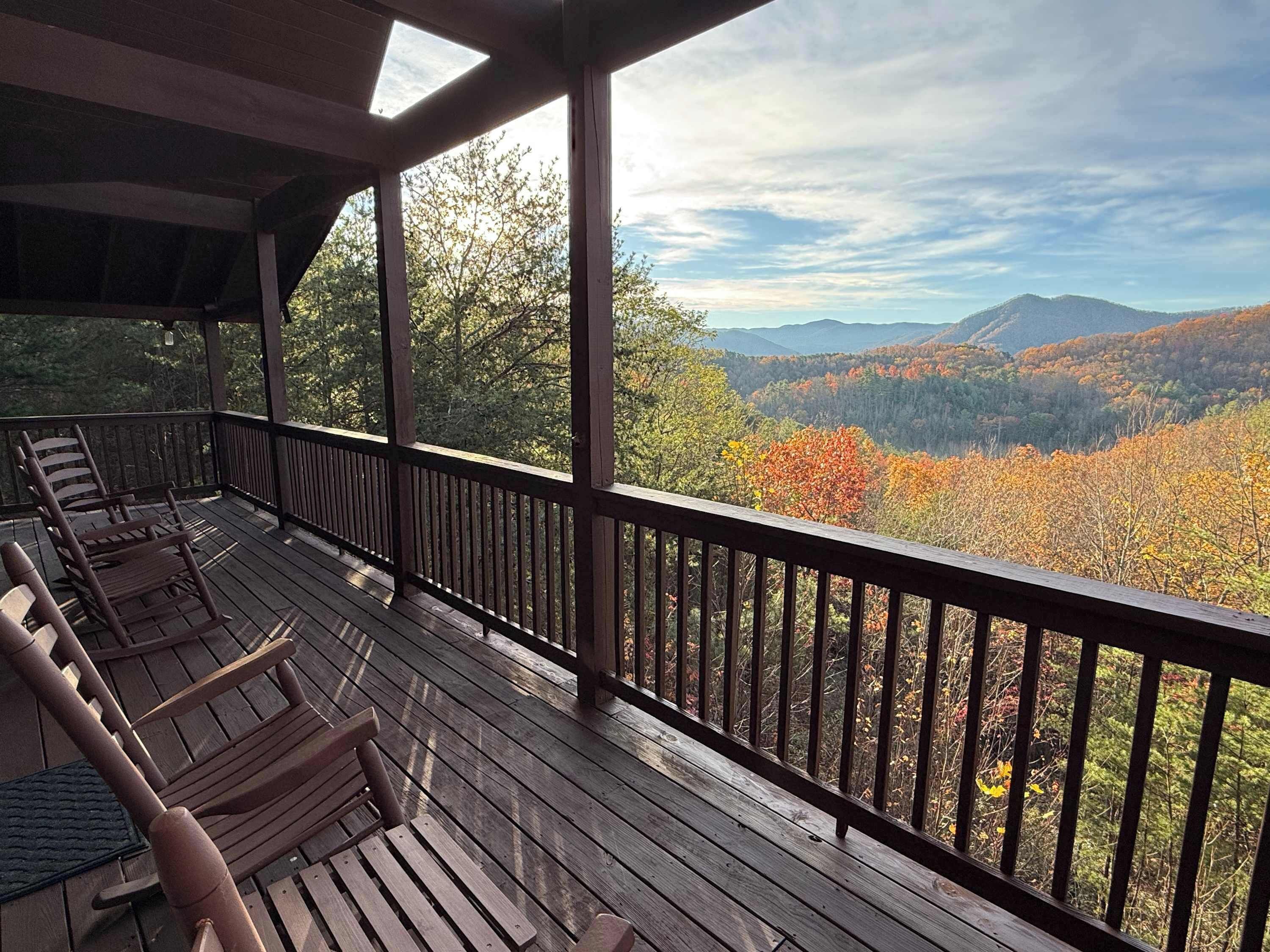 Una terraza de madera con vistas a un valle boscoso y montañas.
