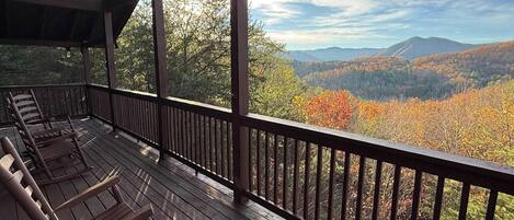 Una terraza de madera con vistas a un valle boscoso y montañas.