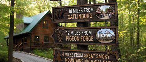 A wooden signpost with distance markers to Elk Lodge, Gatlinburg, Pigeon Forge, and Great Smoky Mountains National Park.