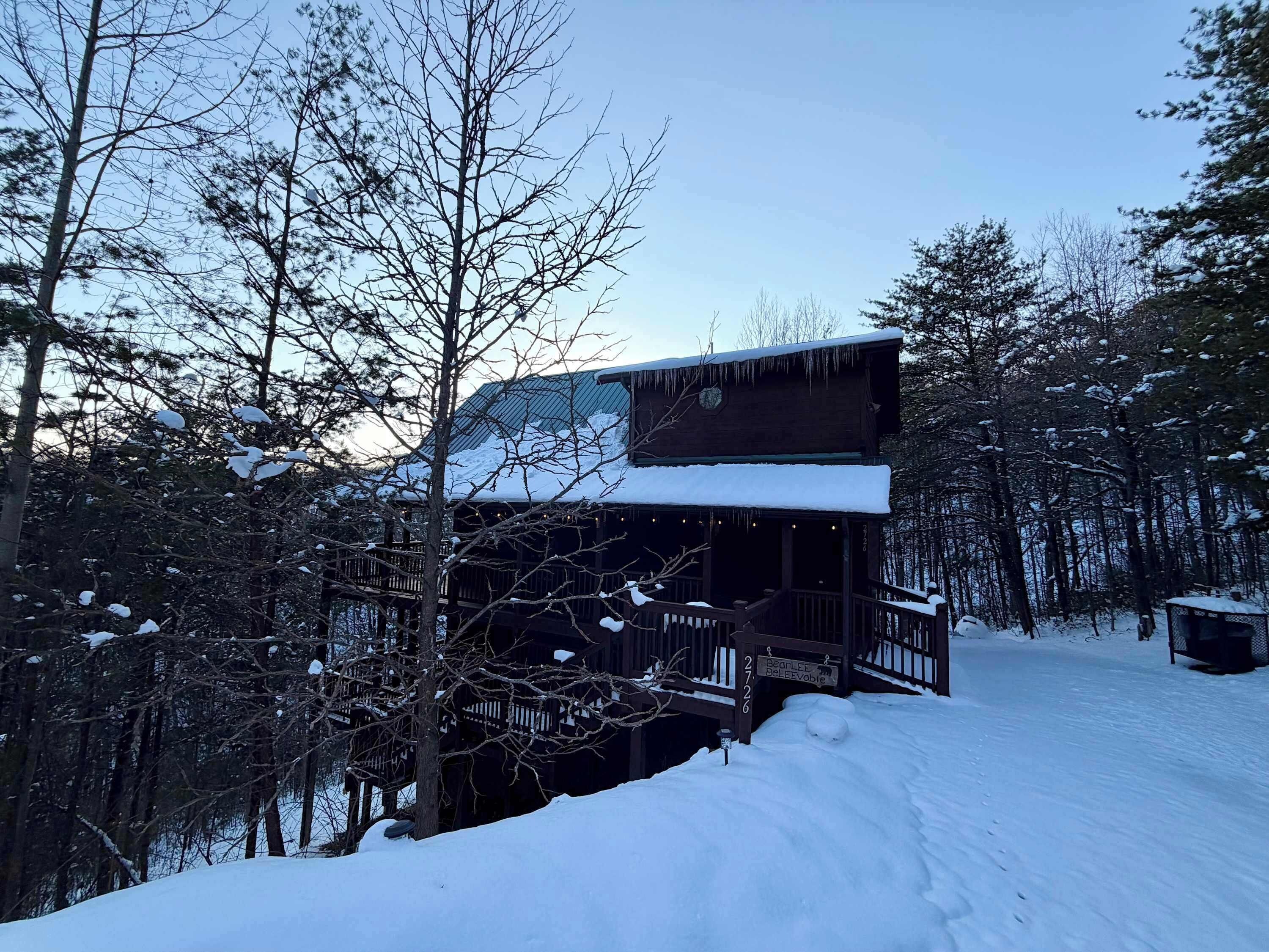 Une cabane en bois à deux étages, dotée d’une terrasse enneigée et d’une enseigne indiquant « 27-26 ».