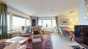 Un salón amplio con un gran ventanal, zona de comedor y un rincón de estar acogedor.