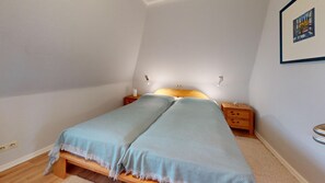 A small, single-bed room with a wooden headboard, two bedside tables, and a framed picture on the wall.