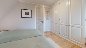 Un dormitorio con dos camas, un armario y una puerta que da a otra habitación.