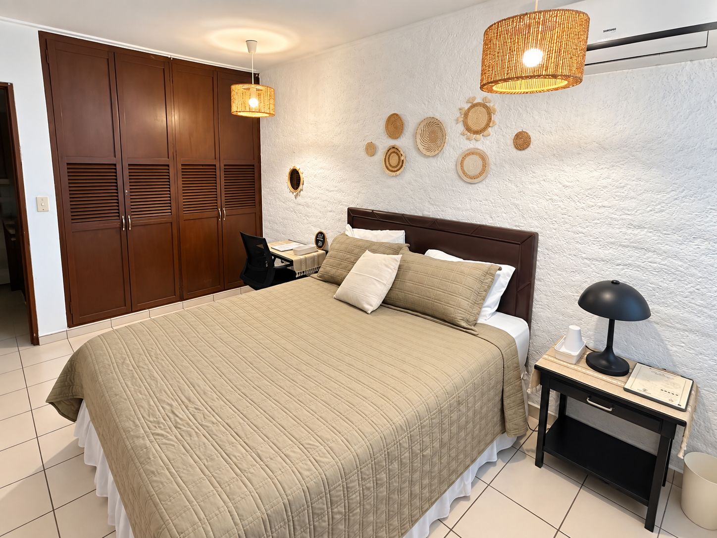 Ein Schlafzimmer mit einem großen Bett, einem Schreibtisch, einem Stuhl, einem Nachttisch und einem Kleiderschrank.