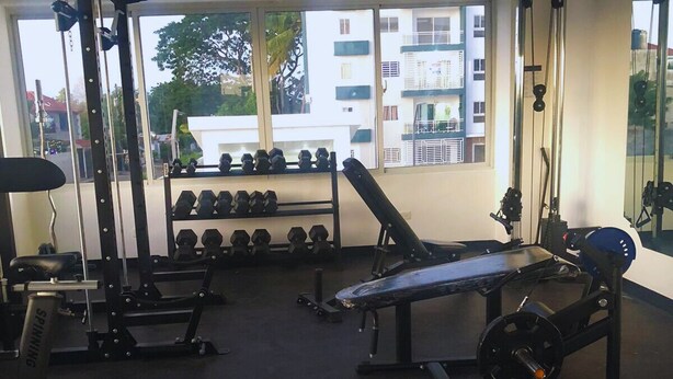 Et fitnesscenter med bænkpresser, håndvægte og løbebånd.
