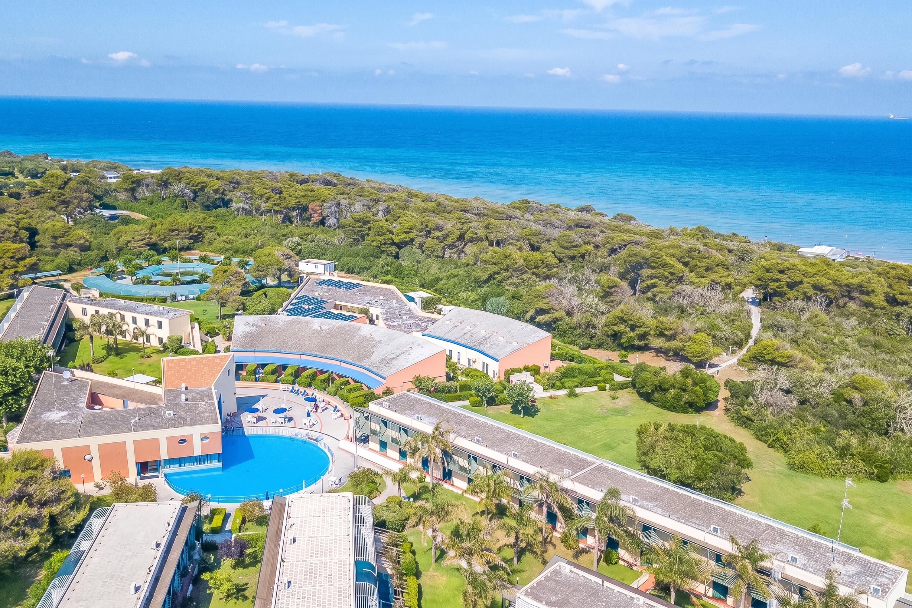 Ein Resort mit einem großen Pool, mehreren Gebäuden und Blick aufs Meer.