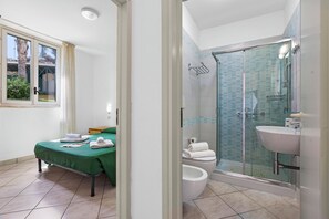 A bathroom with a glass shower enclosure, a toilet, and a sink.