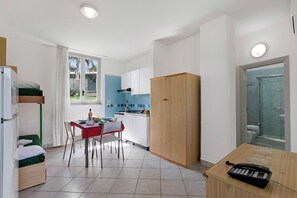 A compact kitchen with a dining area, a small table with a phone, and a view of the outside.