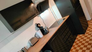 Une cuisine équipée d’un plan de travail en bois, d’un four à micro-ondes, d’une bouilloire et d’une machine à café.