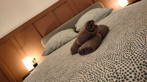 Un lit bien fait, avec une couvre-lit à motifs et deux oreillers, une tête de lit en bois et deux lampes de chevet.