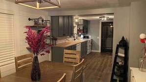 A modern kitchen with wooden cabinets, a central island, and a dining area with a wooden table and chairs. - Quiet & charming 3-bedroom, 3-story house located in Butler, Ohio. (Butler)