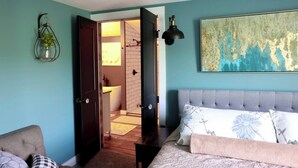 A bedroom with a bed, a bedside table, a chair, a wall-mounted lamp, and a painting. - Quiet & charming 3-bedroom, 3-story house located in Butler, Ohio. (Butler)