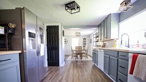 A modern kitchen with a central island, stainless steel appliances, and a dining area with a wooden table and chairs. - Quiet & charming 3-bedroom, 3-story house located in Butler, Ohio. (Butler)