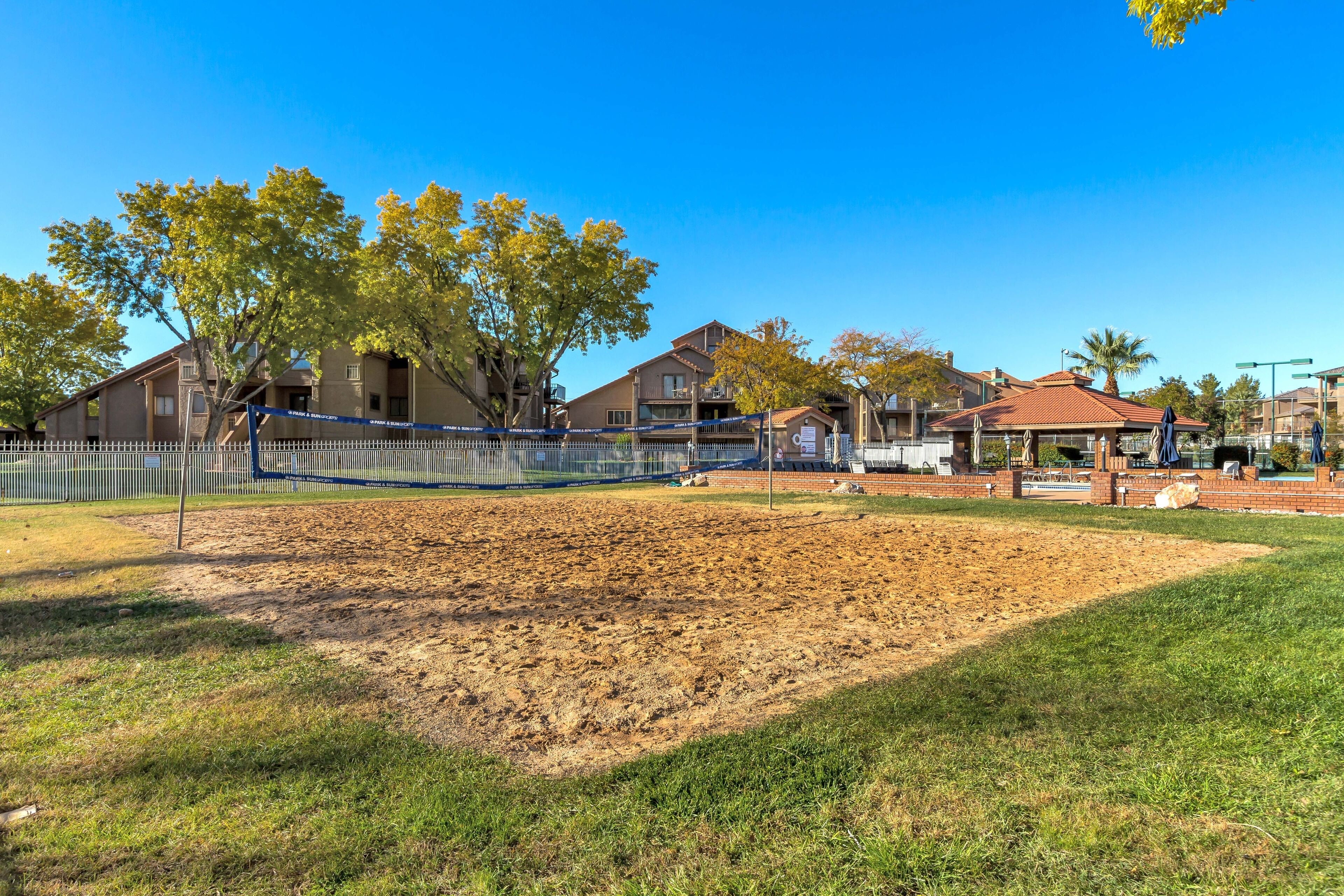 Ein Baseballfeld mit einem Zaun, Bäumen und Gebäuden im Hintergrund.