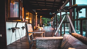A cozy outdoor seating area with wicker furniture, a telescope, and a view of the outdoors.