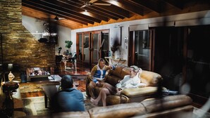 A cozy living room with a stone wall, wooden ceiling, and a leather couch.
