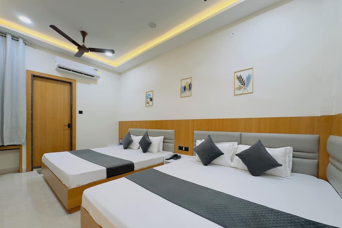 A hotel room with two beds, a ceiling fan, an air conditioning unit, and framed artwork on the walls.