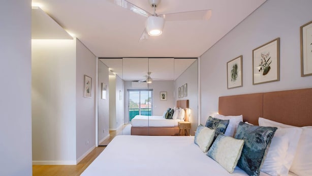 A modern hotel room with a large bed, a second bed, a balcony, and framed botanical illustrations on the wall. - Maestro Park Residence (Cascais)