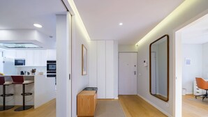 A modern kitchen with white cabinets, a wooden bench, and a large mirror. - Maestro Park Residence (Cascais)