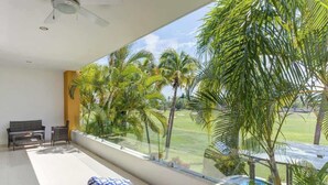 A balcony with a view of palm trees and a pool. - El Tigre Deluxe Stay w/ Pool & Golf views. Large Terrace & BBQ (Nuevo Vallarta)