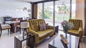 Una sala de estar moderna con un sofá, sillones, una mesa de centro de vidrio y un comedor con una mesa y sillas.