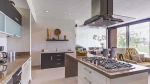 Una cocina moderna con una isla central, electrodomésticos integrados y una zona de comedor con vistas.