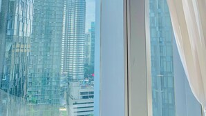 A view through a window with a curtain, featuring modern high-rise buildings and a clear sky. - Star Sky Park KLCC (Kuala Lumpur)