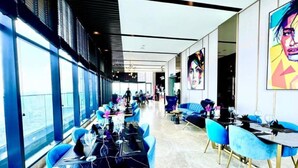A modern dining area with tables and blue chairs, large windows, and artwork on the walls. - Star Sky Park KLCC (Kuala Lumpur)