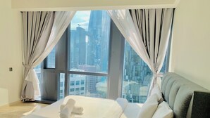 A hotel room with a large bed, white linens, and sheer curtains. - Star Sky Park KLCC (Kuala Lumpur)