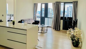A modern living room with a sofa, a dining table, and a large window with curtains. - Star Sky Park KLCC (Kuala Lumpur)
