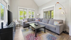 A living room with a gray sofa, a coffee table, a TV, and a floor lamp. - The Jackrabbit  - 3 Summer Village (Prince Edward)