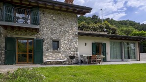 A stone house with a balcony, a dining area, and a barbecue setup. - La Casetta sul Lago by Interhome (Iseo)