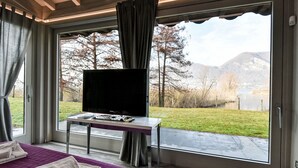 A bedroom with a large window, a bed, a flat-screen TV, and a small table. - La Casetta sul Lago by Interhome (Iseo)