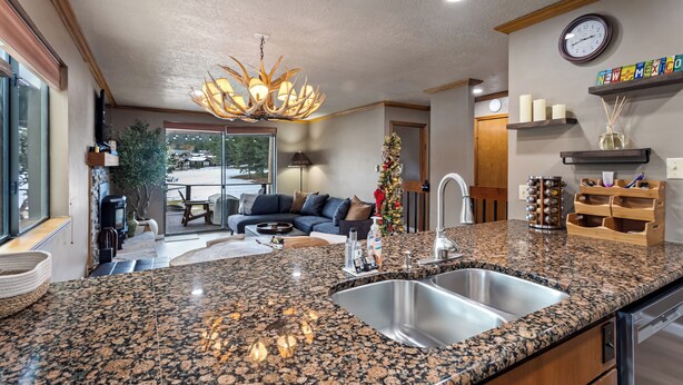 A kitchen with granite countertops, stainless steel sink, and a chandelier. - Updated Angel Fire Golf Lodge (Angel Fire)