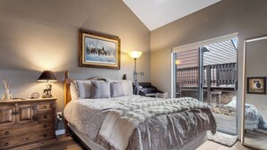 A bedroom with a large bed, a dresser, a lamp, and a painting on the wall. - Updated Angel Fire Golf Lodge (Angel Fire)