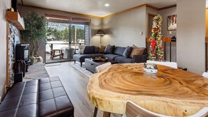 A modern living room with a wooden dining table, a sofa, and a large window. - Updated Angel Fire Golf Lodge (Angel Fire)