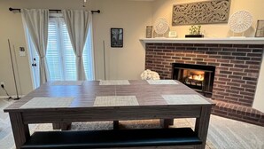 Een eethoek met een grote houten tafel, een bank en een open haard.