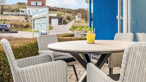Un bâtiment bleu avec une enseigne indiquant « Kurhausappartementen » et une table avec des chaises à l’extérieur.