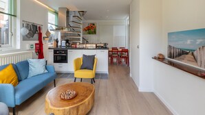 A modern living room with a sofa, a coffee table, and a dining area with chairs.