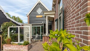 A brick house with a covered patio, a glass door, and a small garden area.