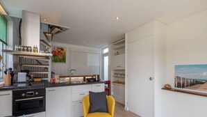 A modern kitchen with white cabinetry, a built-in oven, and a yellow chair.