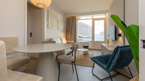 Un salon moderne avec une table ronde, des canapés et un téléviseur fixé au mur.