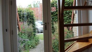 A room with a door leading to a garden, a wooden staircase, and a doormat. - Pretty Holiday Home in Burgerburg (Burgerbrug)